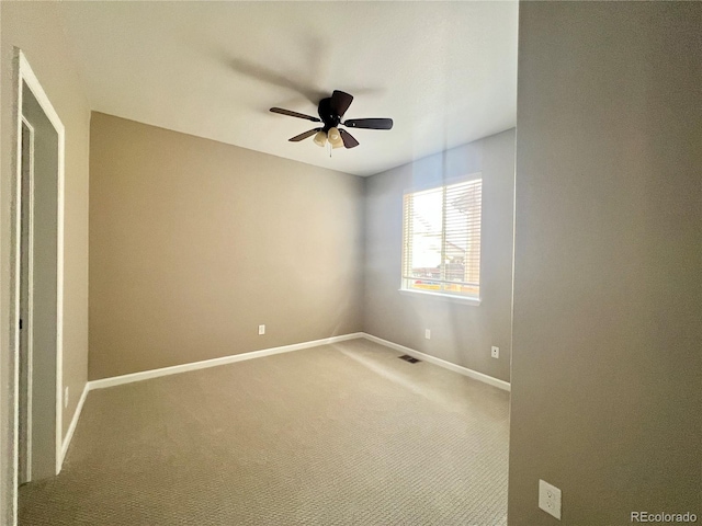 carpeted spare room with visible vents, baseboards, and ceiling fan