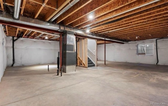 unfinished basement with heating unit and stairs