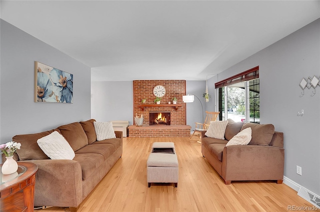 living area with visible vents, light wood finished floors, and a brick fireplace