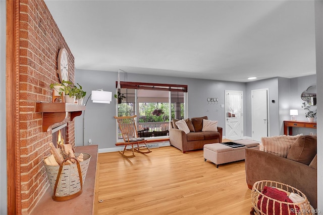 living room featuring a brick fireplace, baseboards, and light wood-style flooring