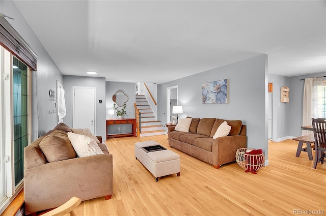 living area featuring baseboards, stairs, and light wood-style flooring