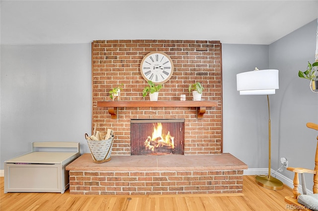 interior details with baseboards, a brick fireplace, and wood finished floors