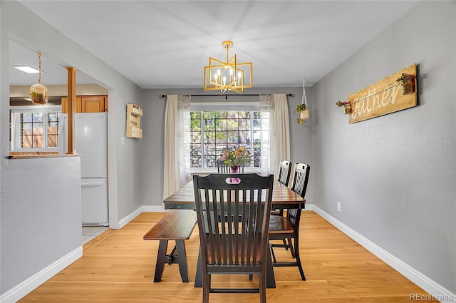 dining room with an inviting chandelier, light wood-style floors, and baseboards