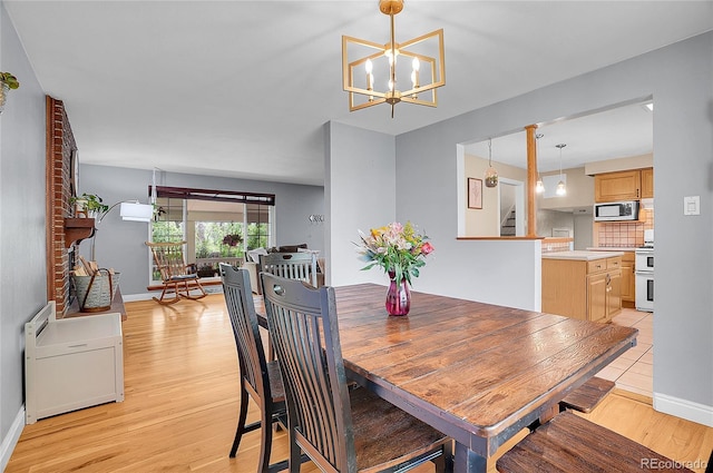 dining space featuring light wood-style floors, baseboards, and a chandelier