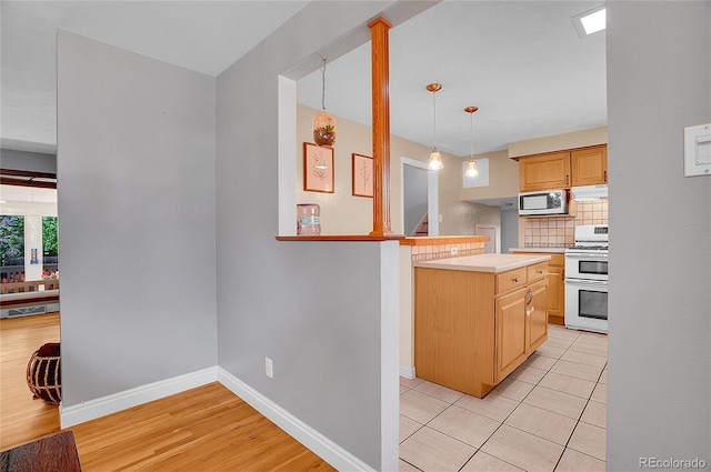 kitchen with light countertops, baseboards, double oven range, tasteful backsplash, and under cabinet range hood