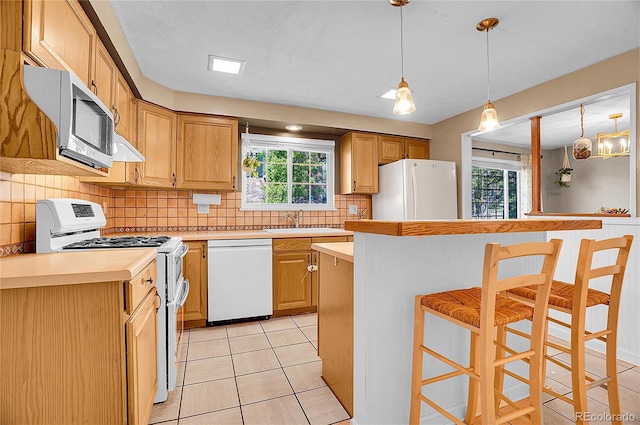 kitchen featuring light countertops, a healthy amount of sunlight, and white appliances