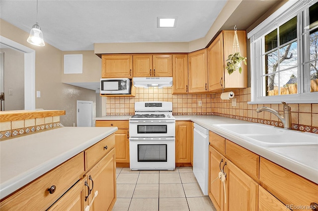 kitchen with a sink, decorative backsplash, under cabinet range hood, and white appliances
