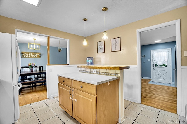kitchen featuring freestanding refrigerator, wainscoting, light tile patterned floors, and light countertops
