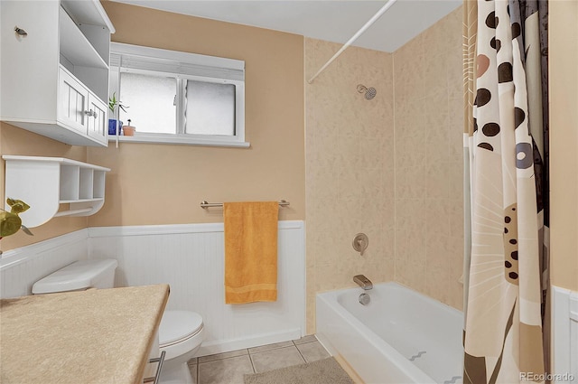 bathroom with toilet, tile patterned floors, wainscoting, and shower / tub combo