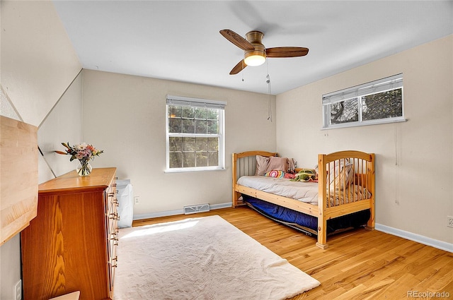 bedroom featuring light wood-type flooring, baseboards, ceiling fan, and visible vents