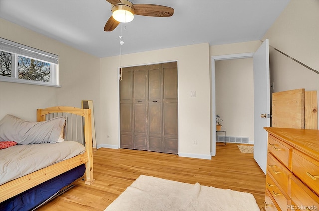 bedroom with baseboards, a ceiling fan, a closet, and light wood-style flooring