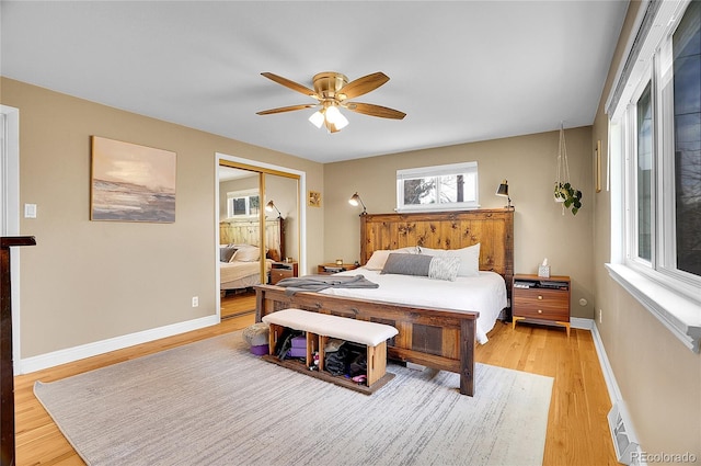 bedroom with light wood-style floors, a ceiling fan, baseboards, and a closet
