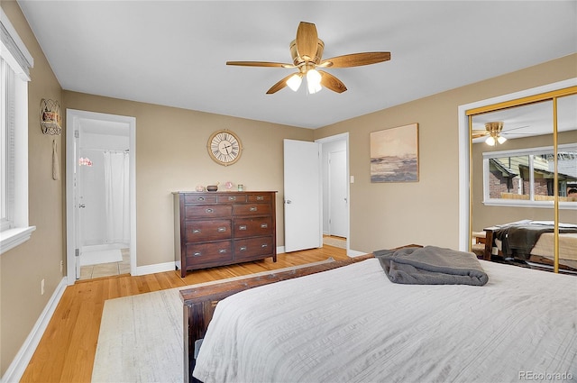 bedroom featuring a closet, baseboards, ceiling fan, light wood-style flooring, and ensuite bath