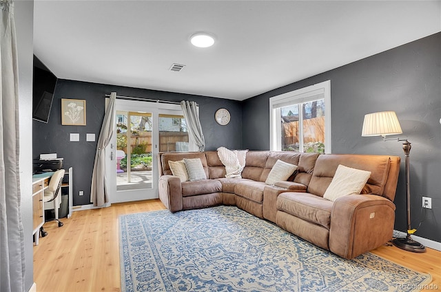 living room featuring baseboards, light wood finished floors, and visible vents