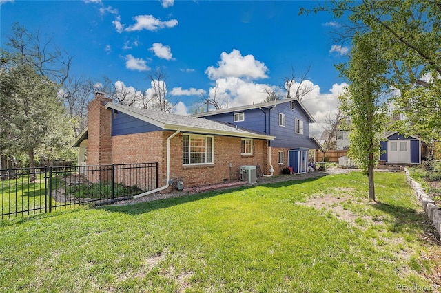 back of house with central AC, a fenced backyard, brick siding, a storage shed, and an outbuilding