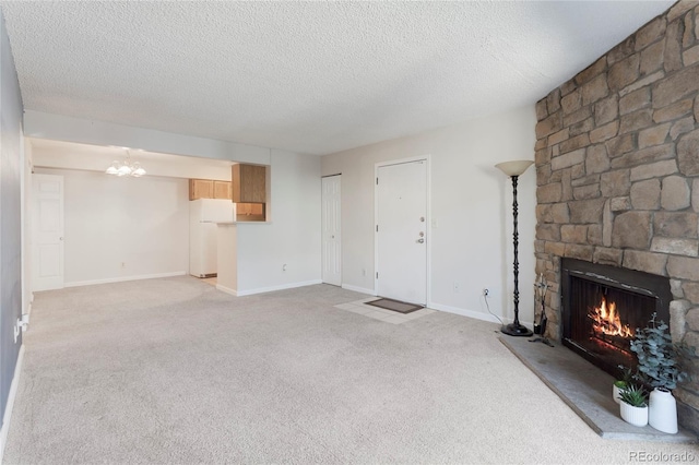 12053 E Harvard Ave Unit 107, Aurora, CO 80014 - unfurnished living room with a stone fireplace, light colored carpet, a textured ceiling, a chandelier, and baseboards