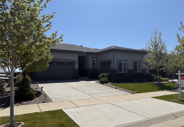 view of front facade with concrete driveway, a garage, a front yard, and stucco siding