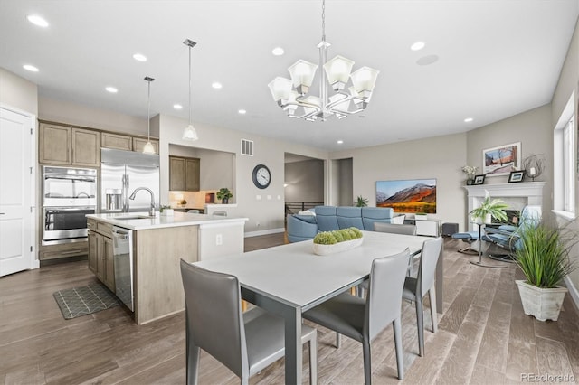dining space featuring dark wood-style flooring, a chandelier, recessed lighting, baseboards, and a fireplace