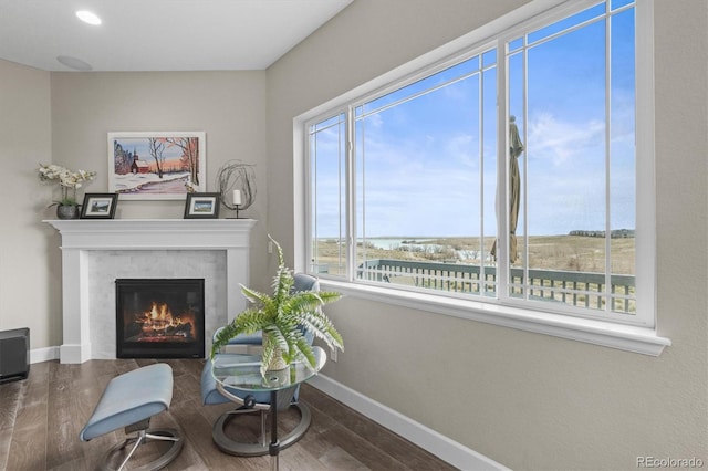 living area with wood finished floors, baseboards, a glass covered fireplace, and recessed lighting