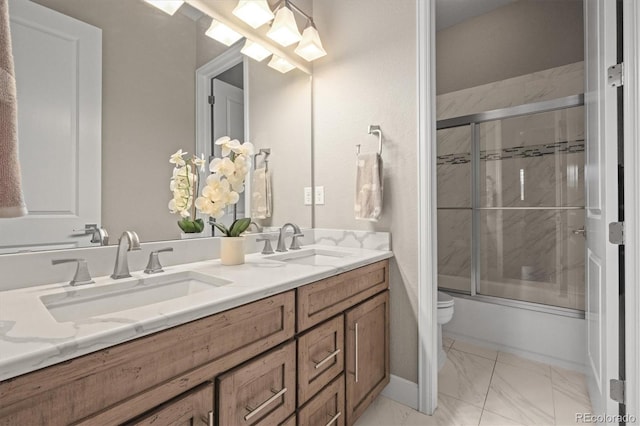 bathroom featuring marble finish floors, toilet, double vanity, and combined bath / shower with glass door