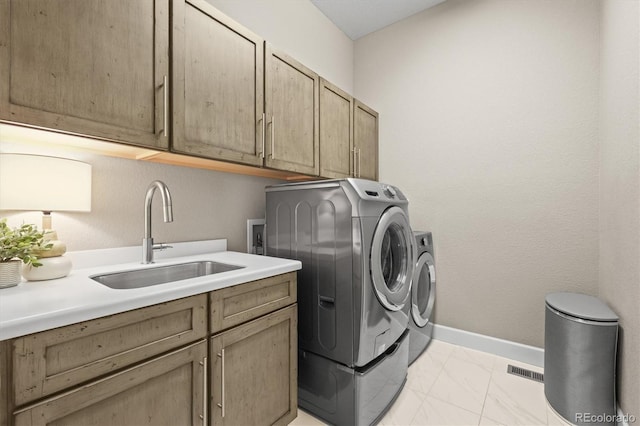 laundry area featuring cabinet space, light marble finish flooring, washer and dryer, and baseboards