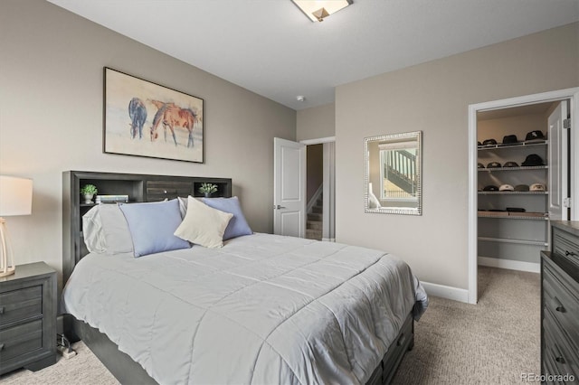 carpeted bedroom with a walk in closet, baseboards, and a closet