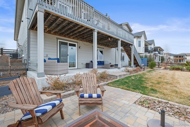 back of property with a wooden deck, a patio area, an outdoor living space, and stairs