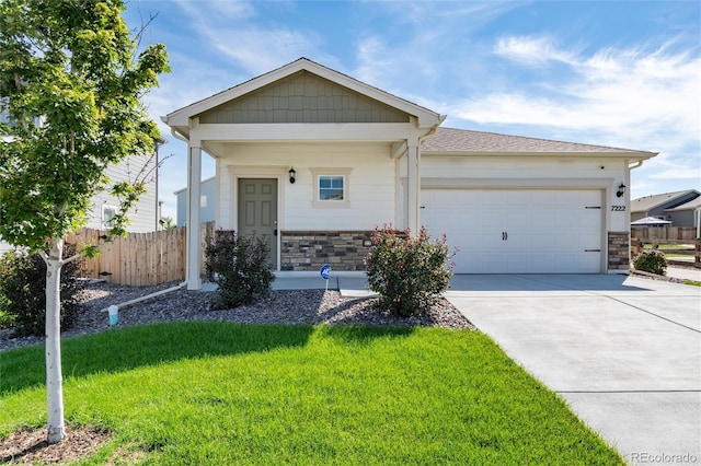 view of front of home featuring concrete driveway, stone siding, an attached garage, fence, and a front yard