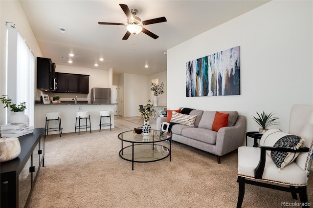 living area featuring a ceiling fan, recessed lighting, visible vents, and light colored carpet