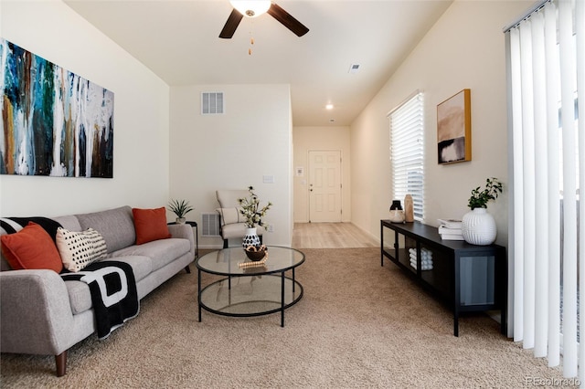 living area with light carpet, visible vents, and a ceiling fan