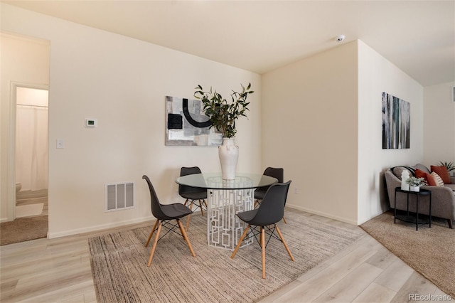 dining room with light wood finished floors, visible vents, and baseboards