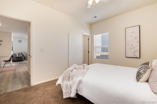 bedroom with ceiling fan, light carpet, visible vents, and baseboards