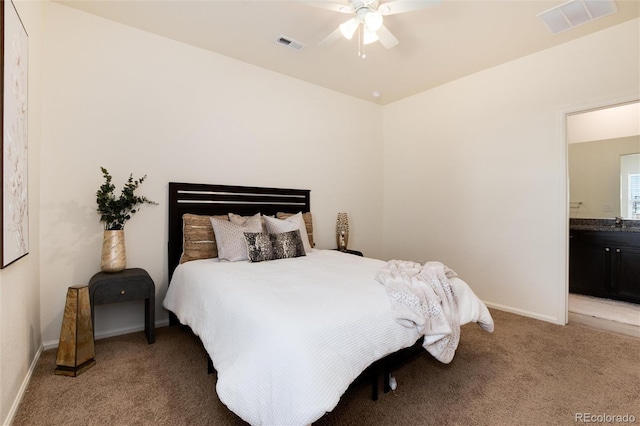 bedroom featuring baseboards, ensuite bath, visible vents, and light colored carpet