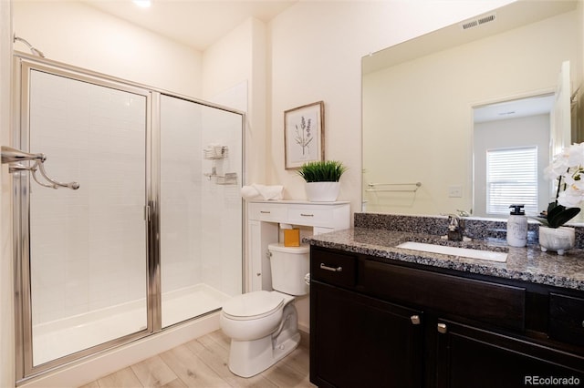 bathroom featuring a stall shower, visible vents, toilet, and wood finished floors