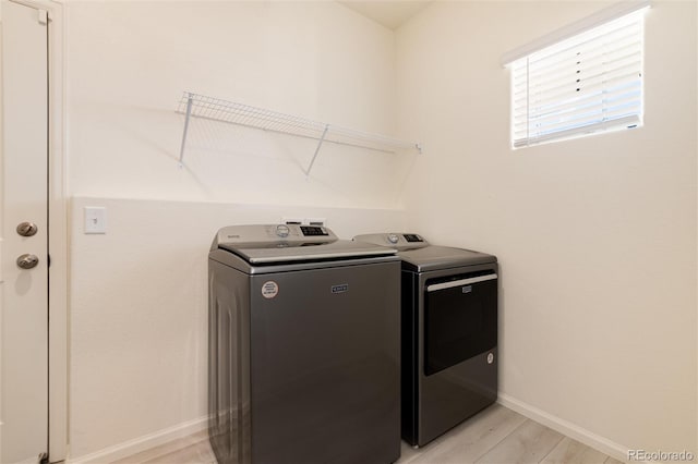 laundry area featuring baseboards, laundry area, light wood-style floors, and washer and dryer