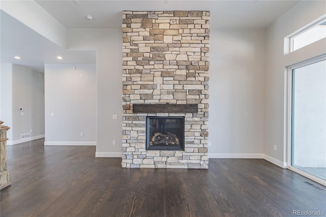 unfurnished living room with a stone fireplace, dark wood-style floors, baseboards, and recessed lighting