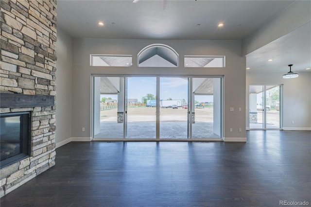 unfurnished living room featuring dark wood-style floors, a fireplace, baseboards, and recessed lighting