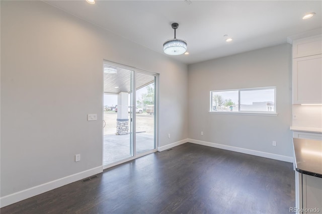 unfurnished dining area with dark wood-style flooring, baseboards, and recessed lighting