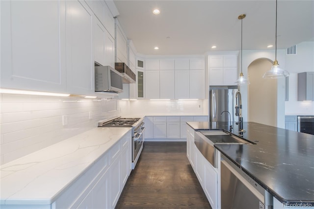 kitchen with stainless steel appliances, white cabinetry, backsplash, a sink, and recessed lighting