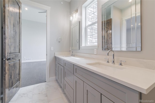 bathroom with marble finish flooring, double vanity, and baseboards