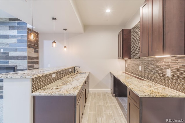 kitchen featuring decorative backsplash, light stone counters, and a peninsula