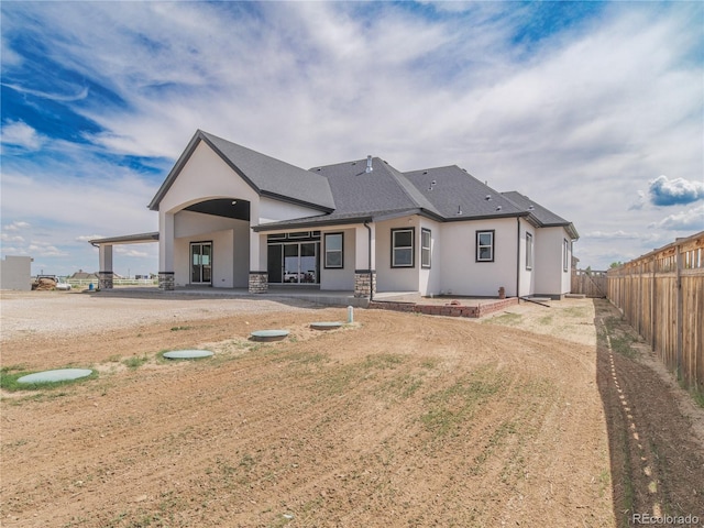 rear view of house with a patio area, stucco siding, a fenced backyard, and a shingled roof