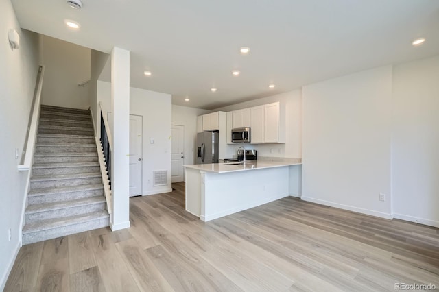 700 N Bently St, Watkins, CO 80137 - kitchen featuring appliances with stainless steel finishes, a peninsula, light countertops, light wood-style floors, and white cabinetry