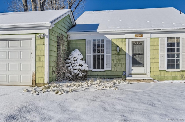 snow covered property entrance with a garage