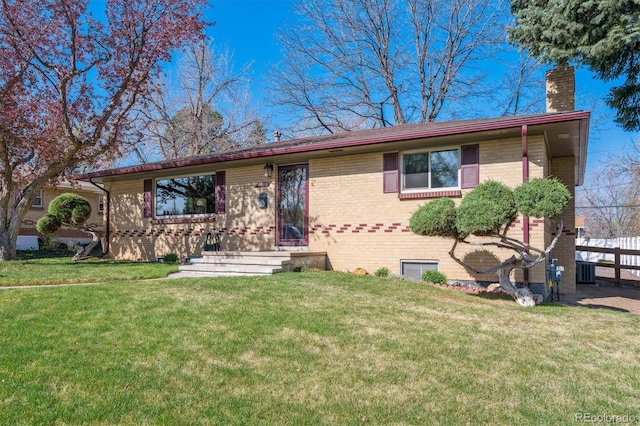 ranch-style home with a front yard, brick siding, central air condition unit, and a chimney