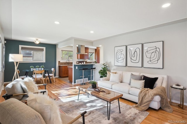 living room with recessed lighting, visible vents, light wood-type flooring, and baseboards