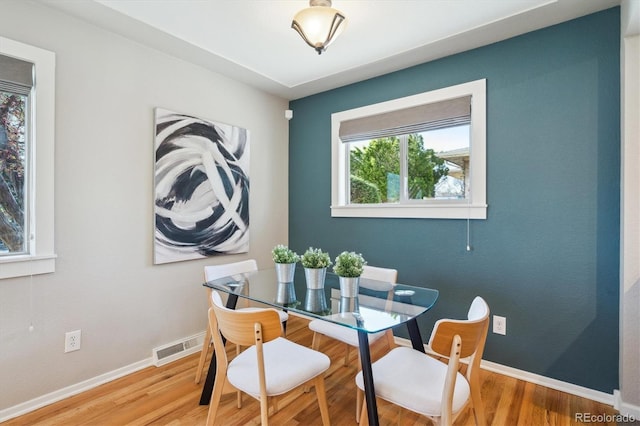 dining room featuring visible vents, baseboards, and wood finished floors