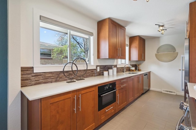 kitchen with visible vents, oven, a sink, stainless steel dishwasher, and decorative backsplash