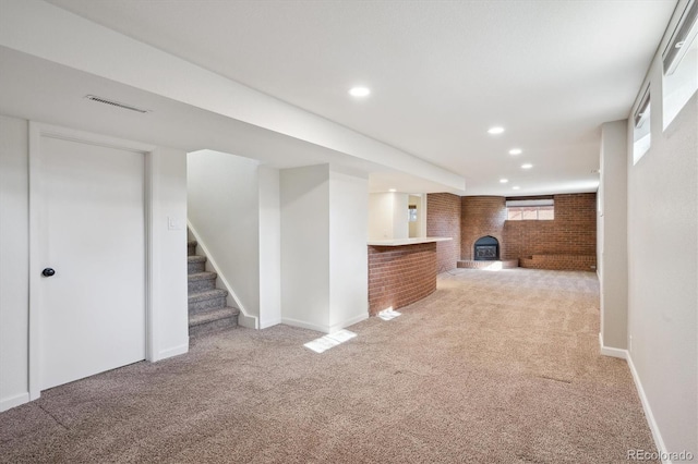 below grade area with visible vents, brick wall, recessed lighting, stairs, and light carpet