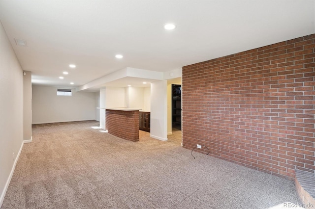 below grade area featuring brick wall, recessed lighting, light colored carpet, and bar area